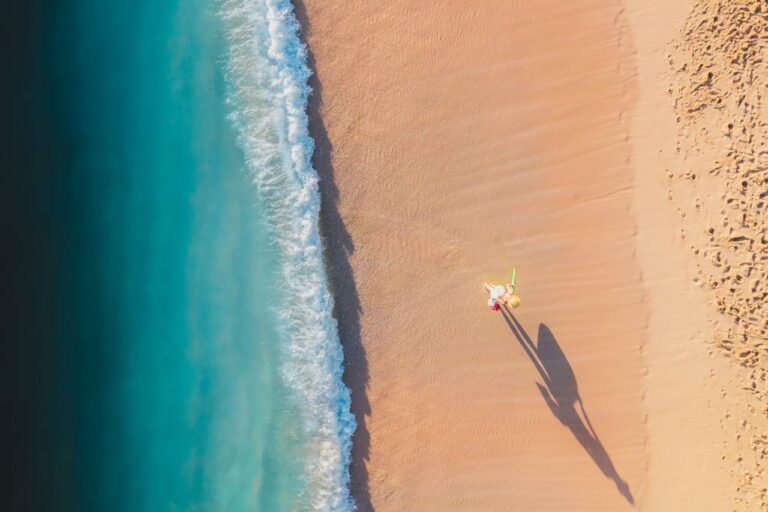 Mulher andando na praia sentindo os benefícios da praia
